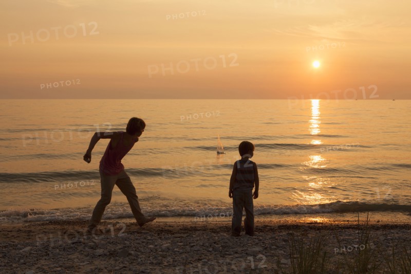 Caucasian brothers playing on beach at sunset