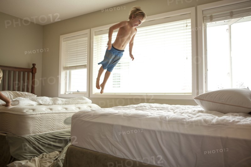 Caucasian boy jumping on bed
