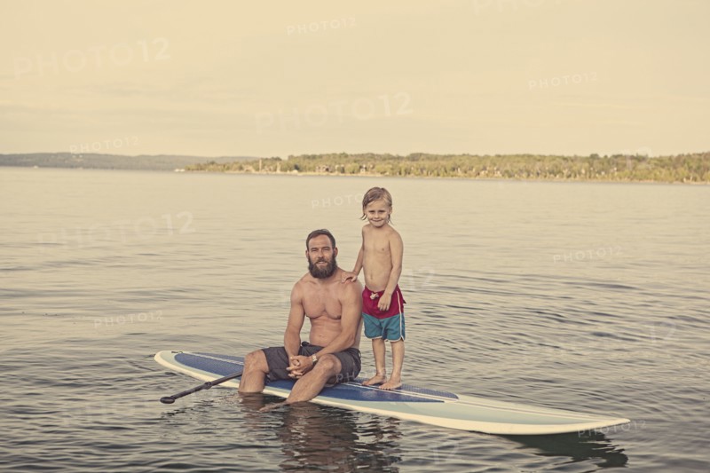 Caucasian father and son on paddleboard in lake