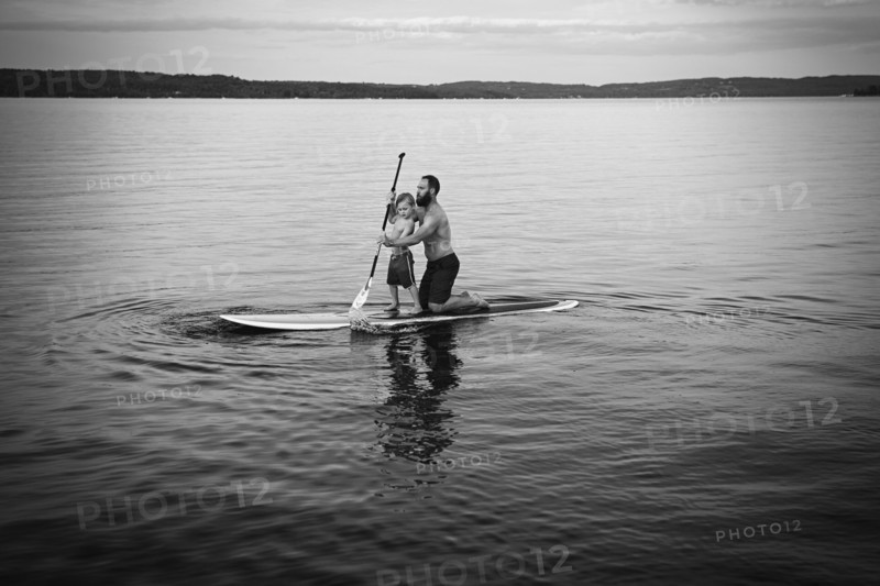 Caucasian father and son on paddleboard in lake
