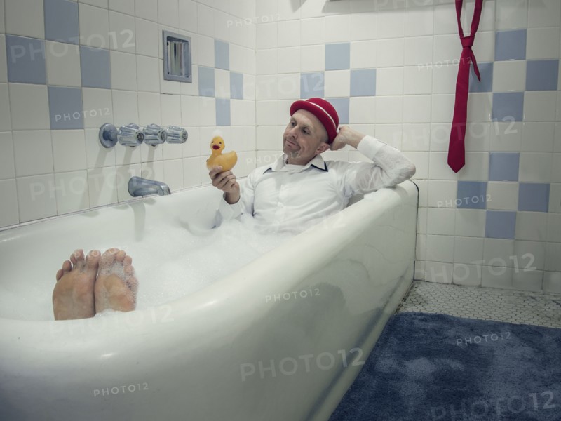 Caucasian businessman wearing clothing in bathtub