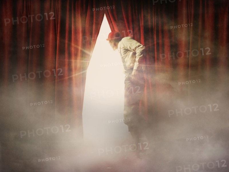 Caucasian man peering through red curtain