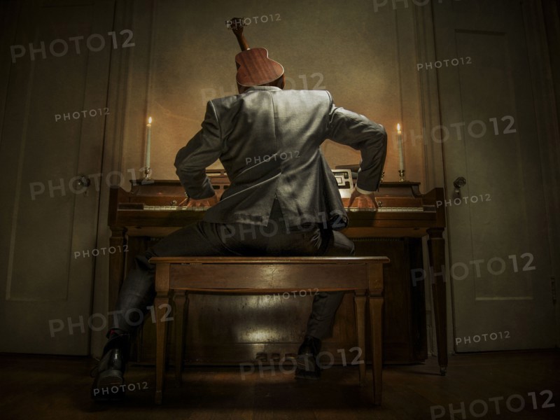 Caucasian musician with ukulele head playing piano