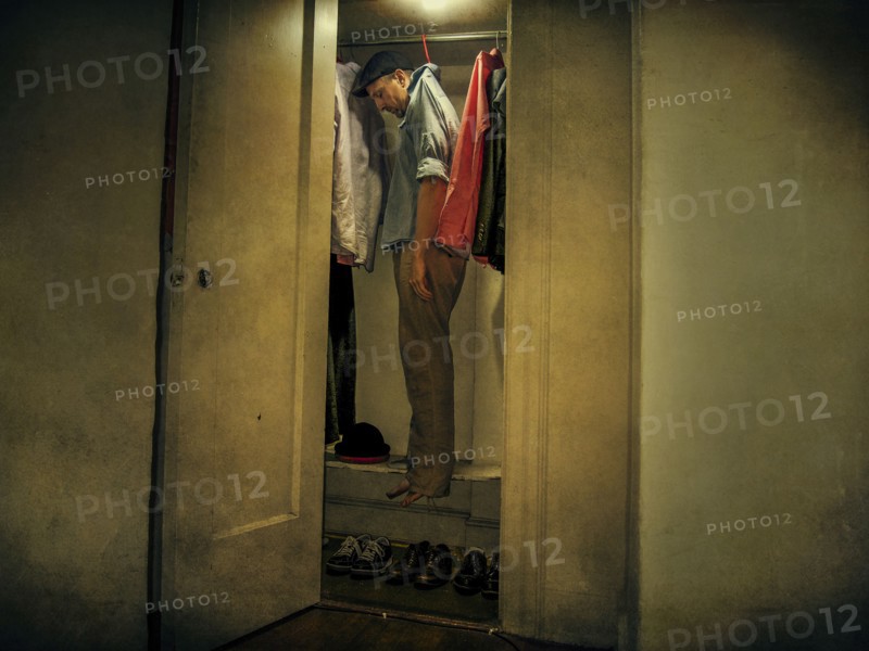 Caucasian man hanging with clothing in closet