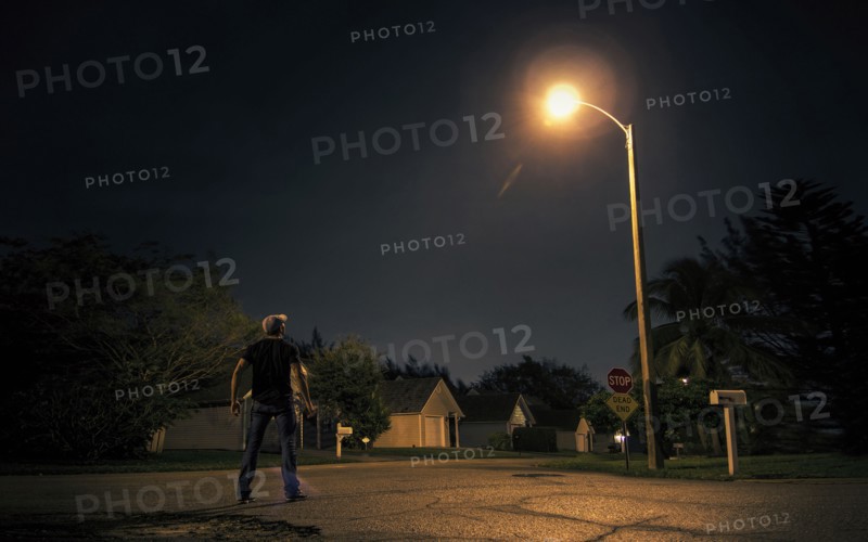 Caucasian man looking up at street light in suburb at night