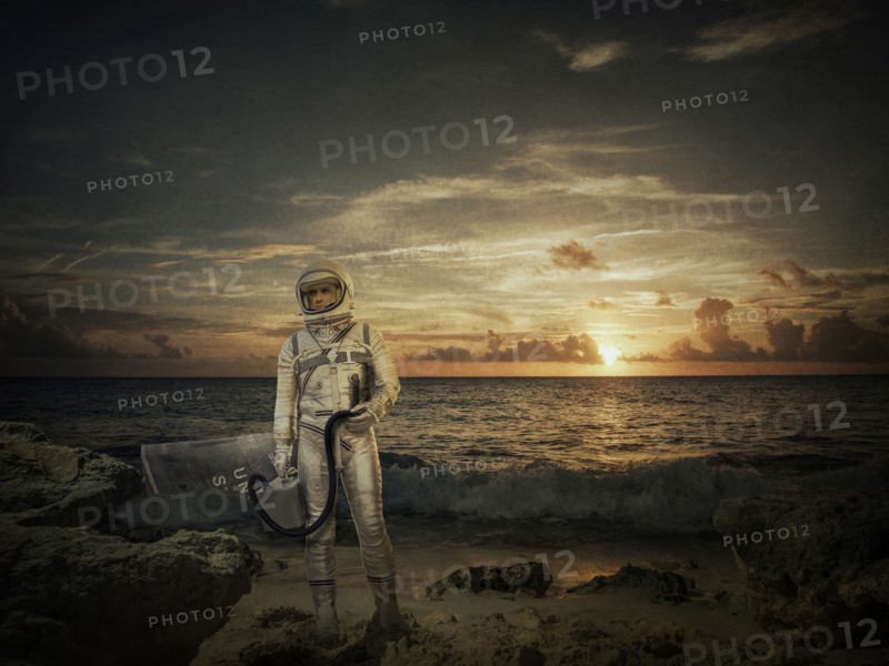 Caucasian astronaut standing on beach at sunset