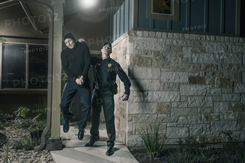 Caucasian police lifting burglar in handcuffs