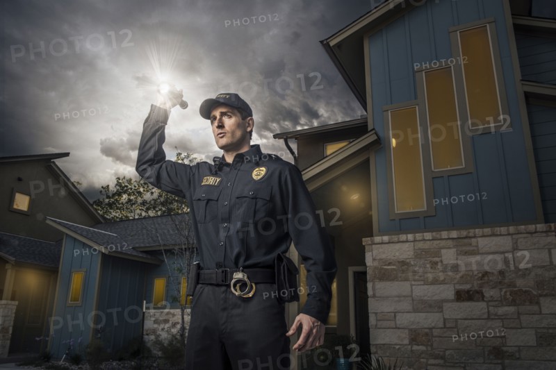 Caucasian police officer shining flashlight near house