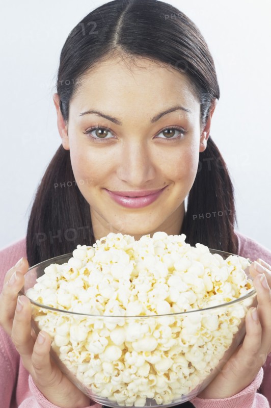 Young woman holding bowl of popcorn