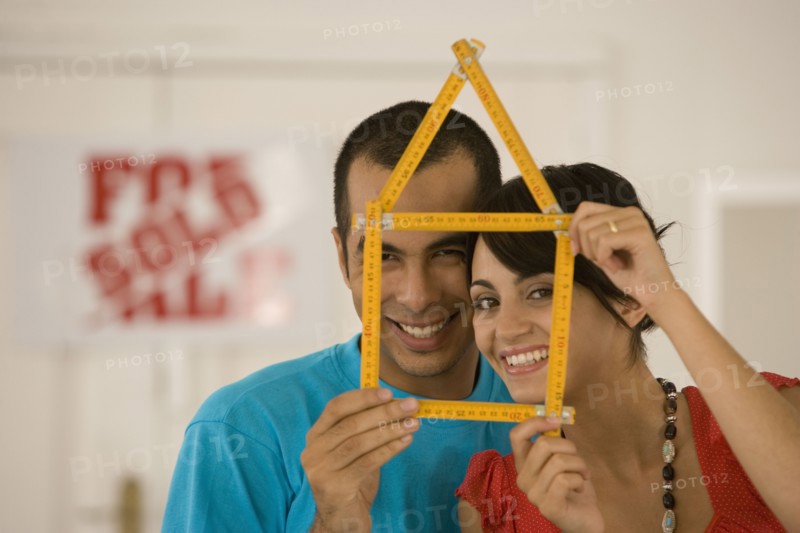 Couple holding folding ruler shaped like house