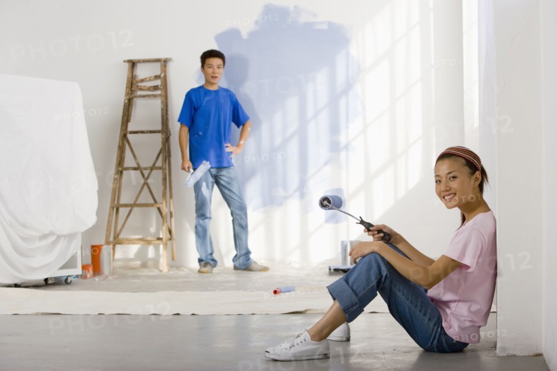 Asian couple painting interior of house