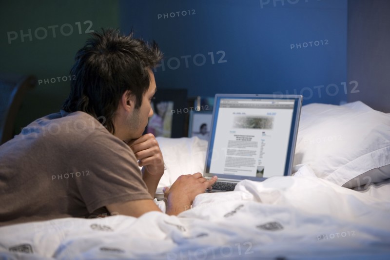 Asian man looking at laptop