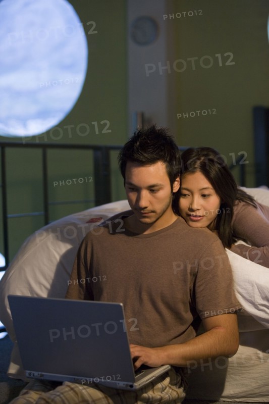 Asian couple looking at laptop