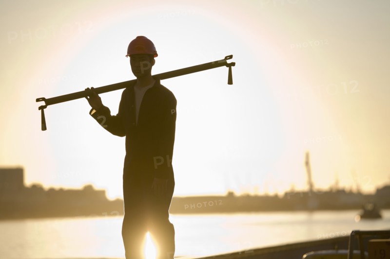 Asian male dock worker holding pipe