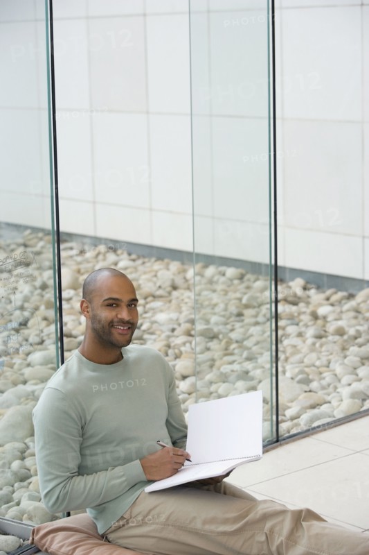 African man writing in notepad