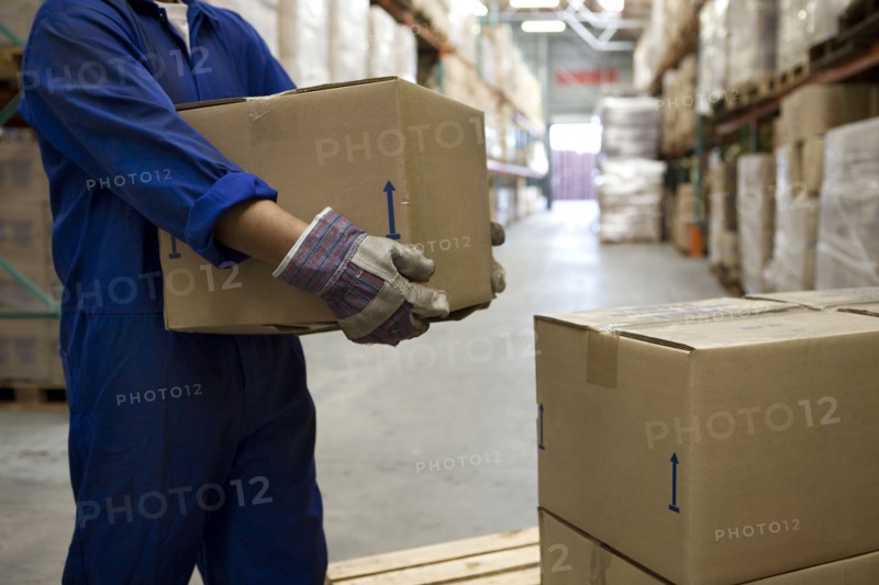 Worker carrying boxes in warehouse