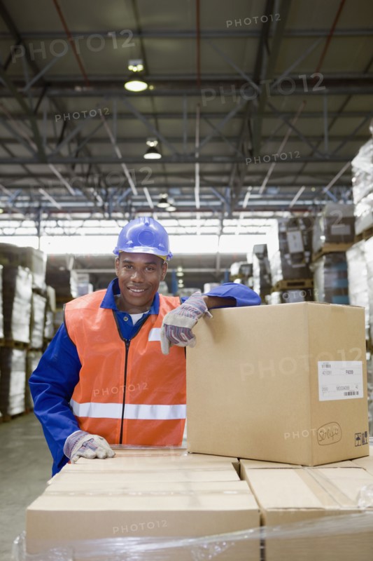 African worker leaning on boxes in warehouse