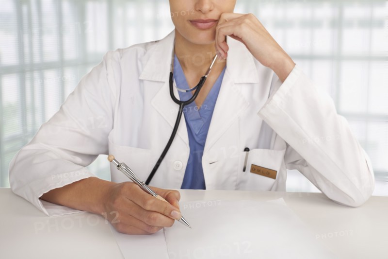 Mixed race doctor writing in hospital