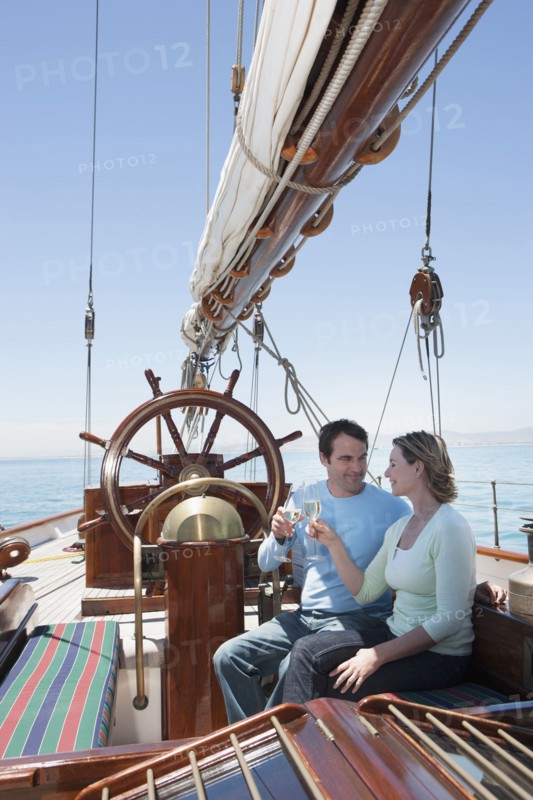 Caucasian couple toasting each other on sailboat