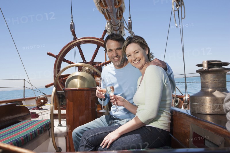 Caucasian couple toasting each other on sailboat