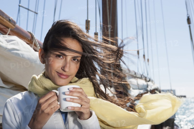 Caucasian woman drinking coffee on sailboat