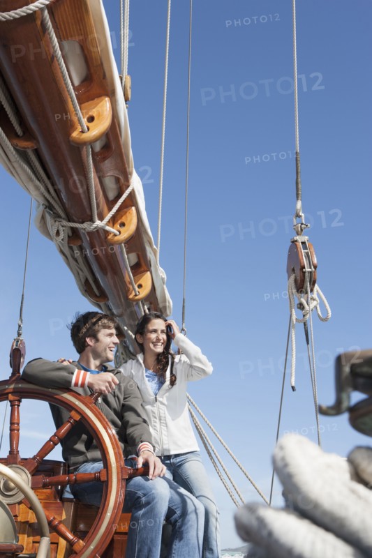 Caucasian couple at helm of sailboat