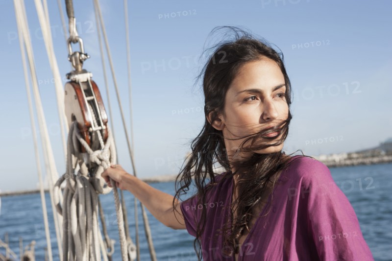 Caucasian woman hoisting sail on sailboat