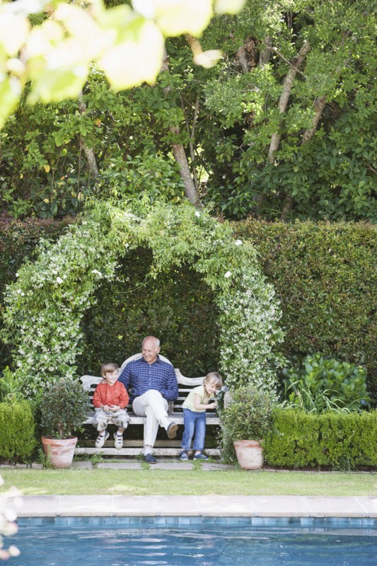 Grandfather sitting with grandchildren on garden bench