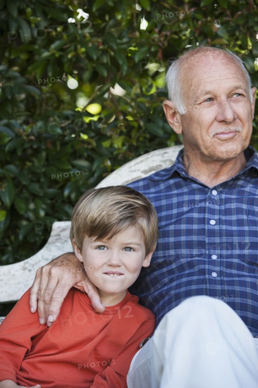 Caucasian boy sitting with grandfather on bench