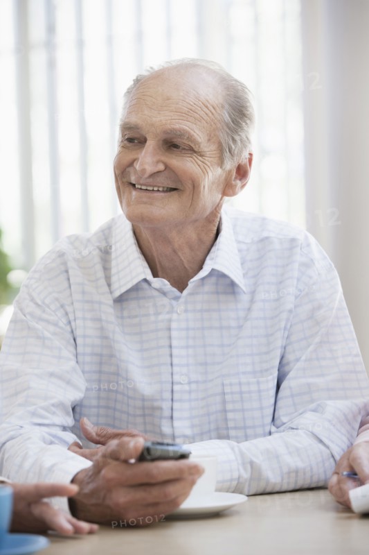 Senior Caucasian man using cell phone in cafe