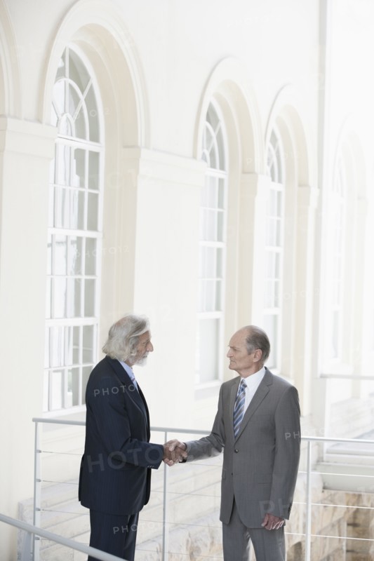Senior Caucasian businessmen shaking hands on balcony
