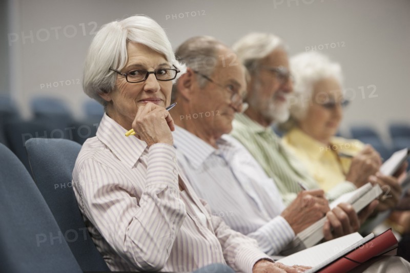Senior Caucasian students taking notes in classroom