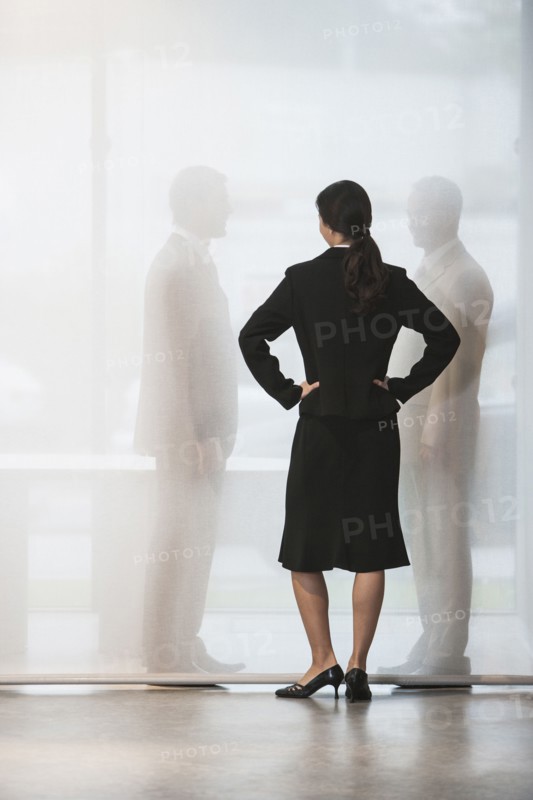 Businesswoman watching colleagues shake hands behind curtain