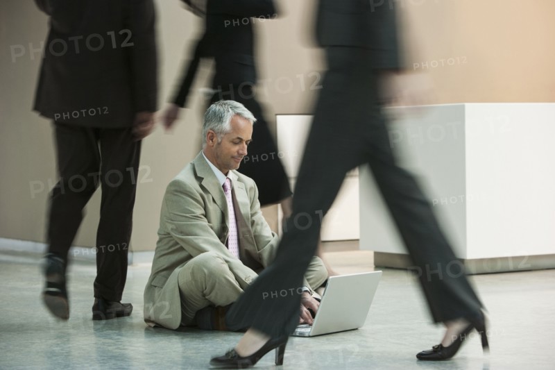 Businessman using laptop on busy office floor
