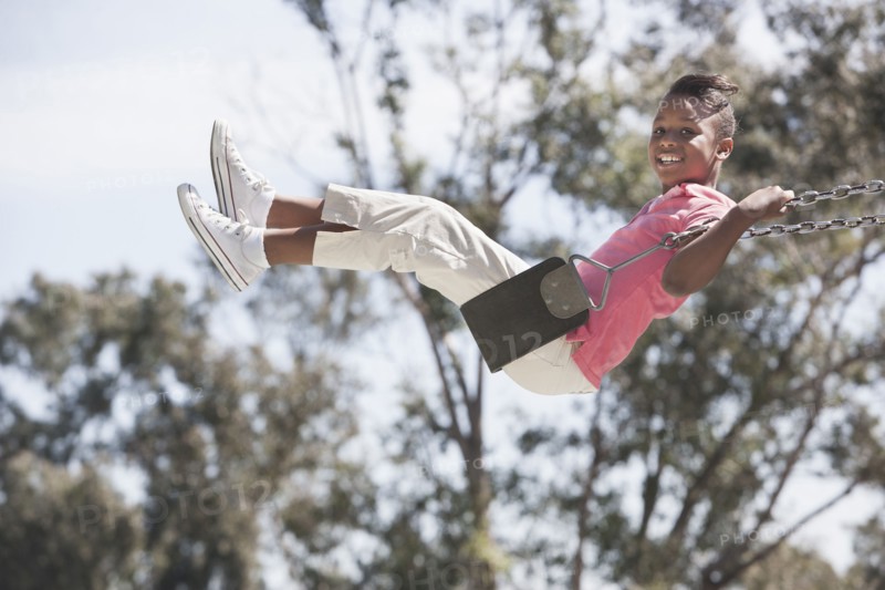 African American girl playing on swing