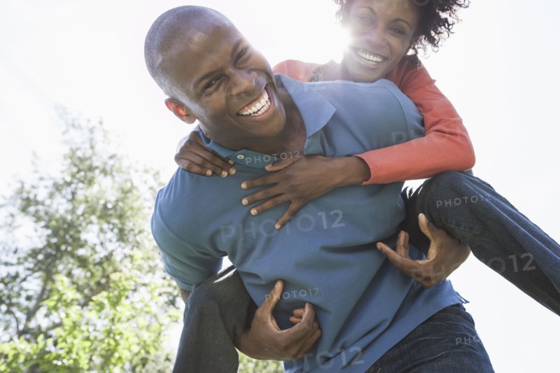 Man carrying girlfriend piggyback in park