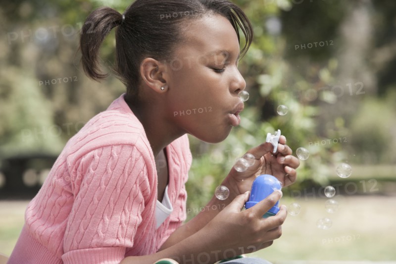 African American girl blowing bubbles outdoors