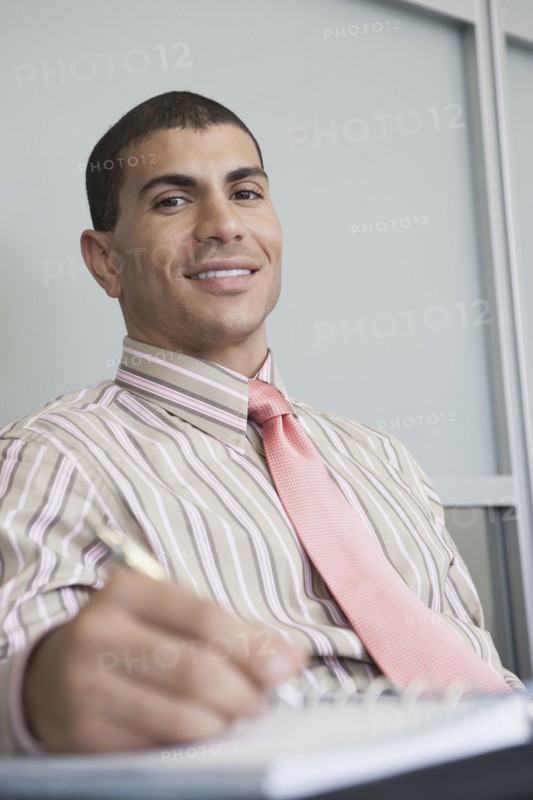 Hispanic businessman taking notes in office