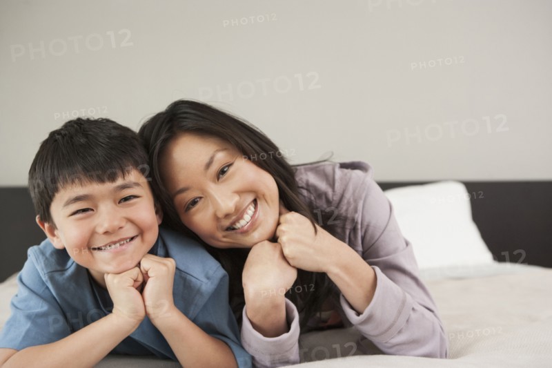 Asian mother and son laying on bed