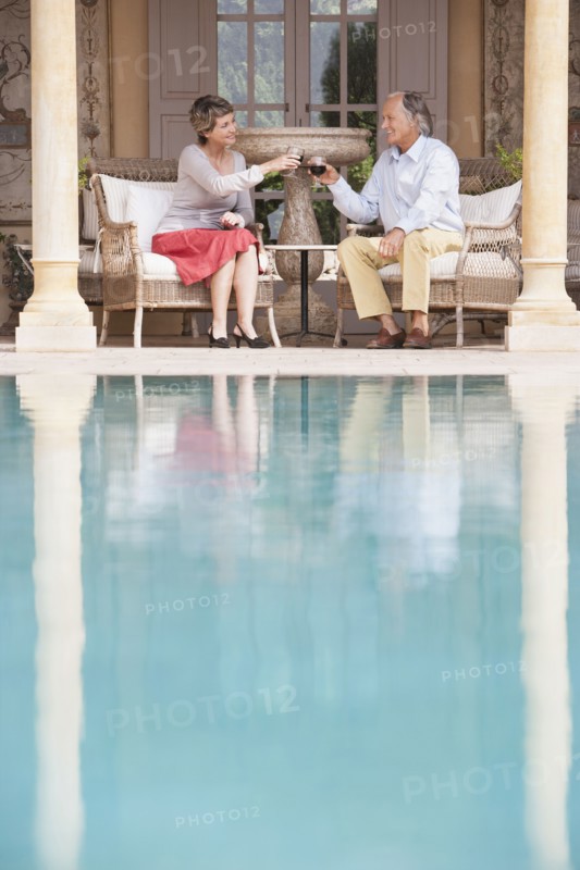 Couple toasting each other by swimming pool