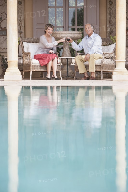 Couple toasting each other by swimming pool