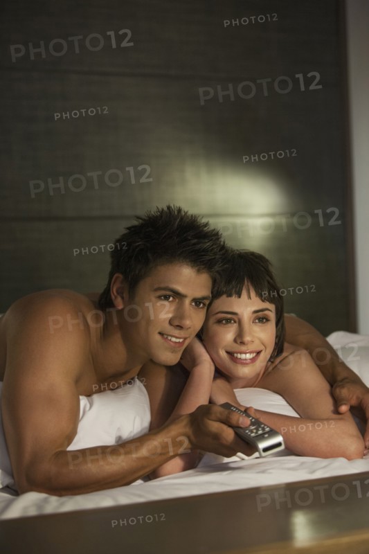 Caucasian couple watching television in bed