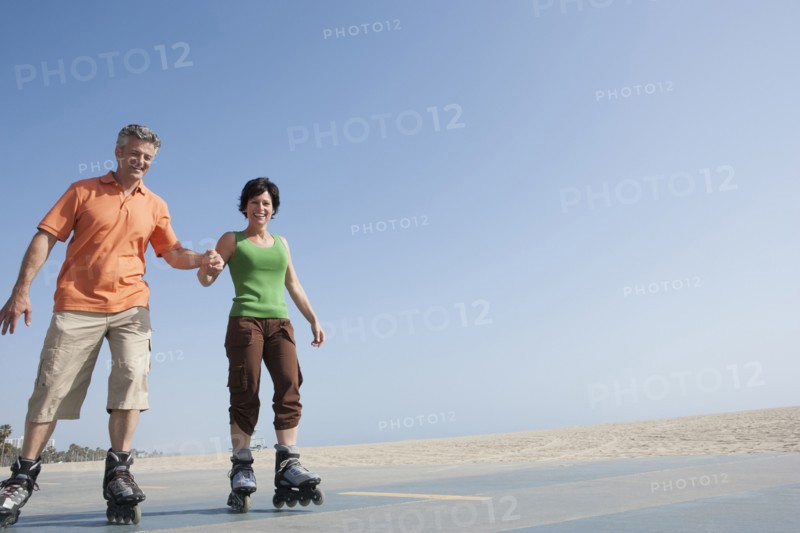 Caucasian couple rollerblading by beach