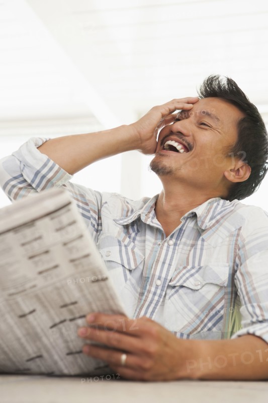 Asian man reading newspaper