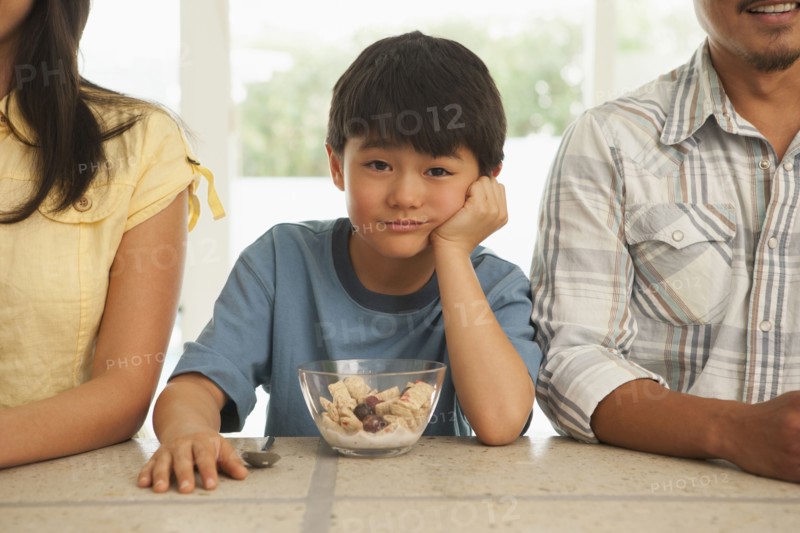 Boy sitting between parents at breakfast table