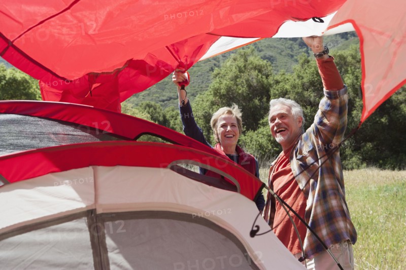 Senior Caucasian couple pitching tent in field