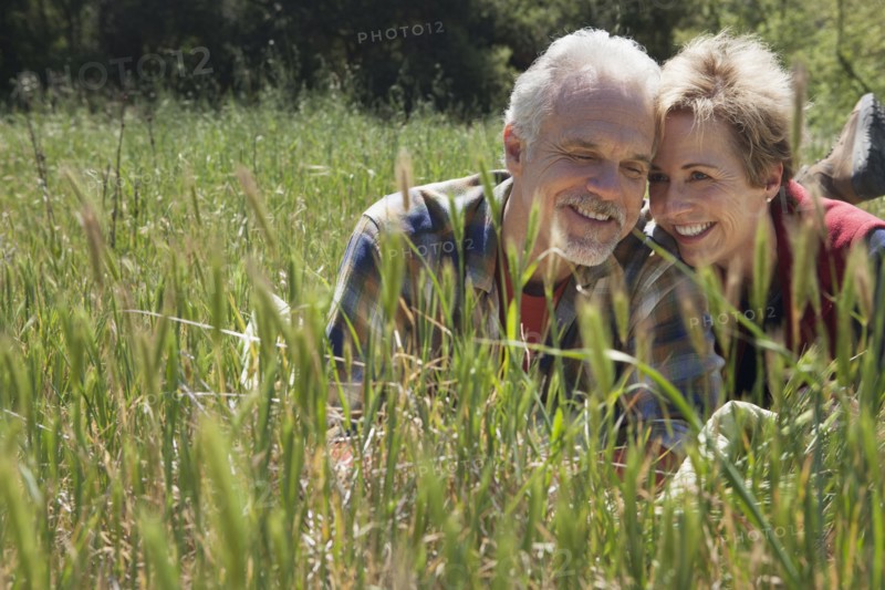 Senior Caucasian couple laying in tall grass