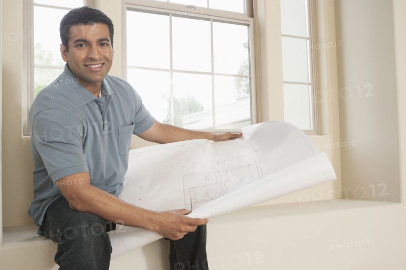 Hispanic man reading blueprints in new home