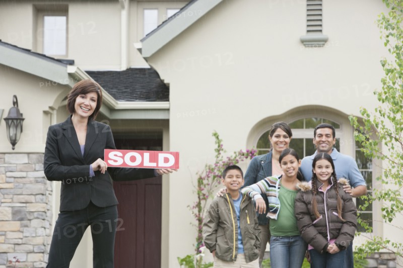 Realtor and family smiling outside new home