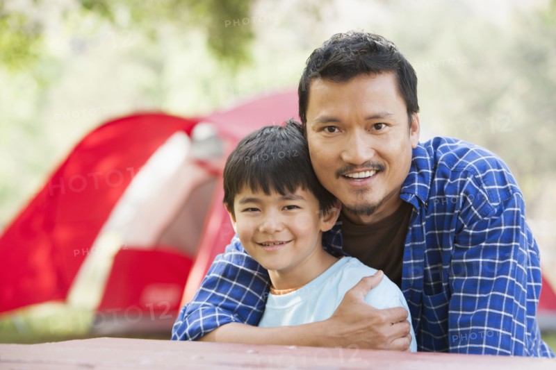 Asian father and son hugging outdoors